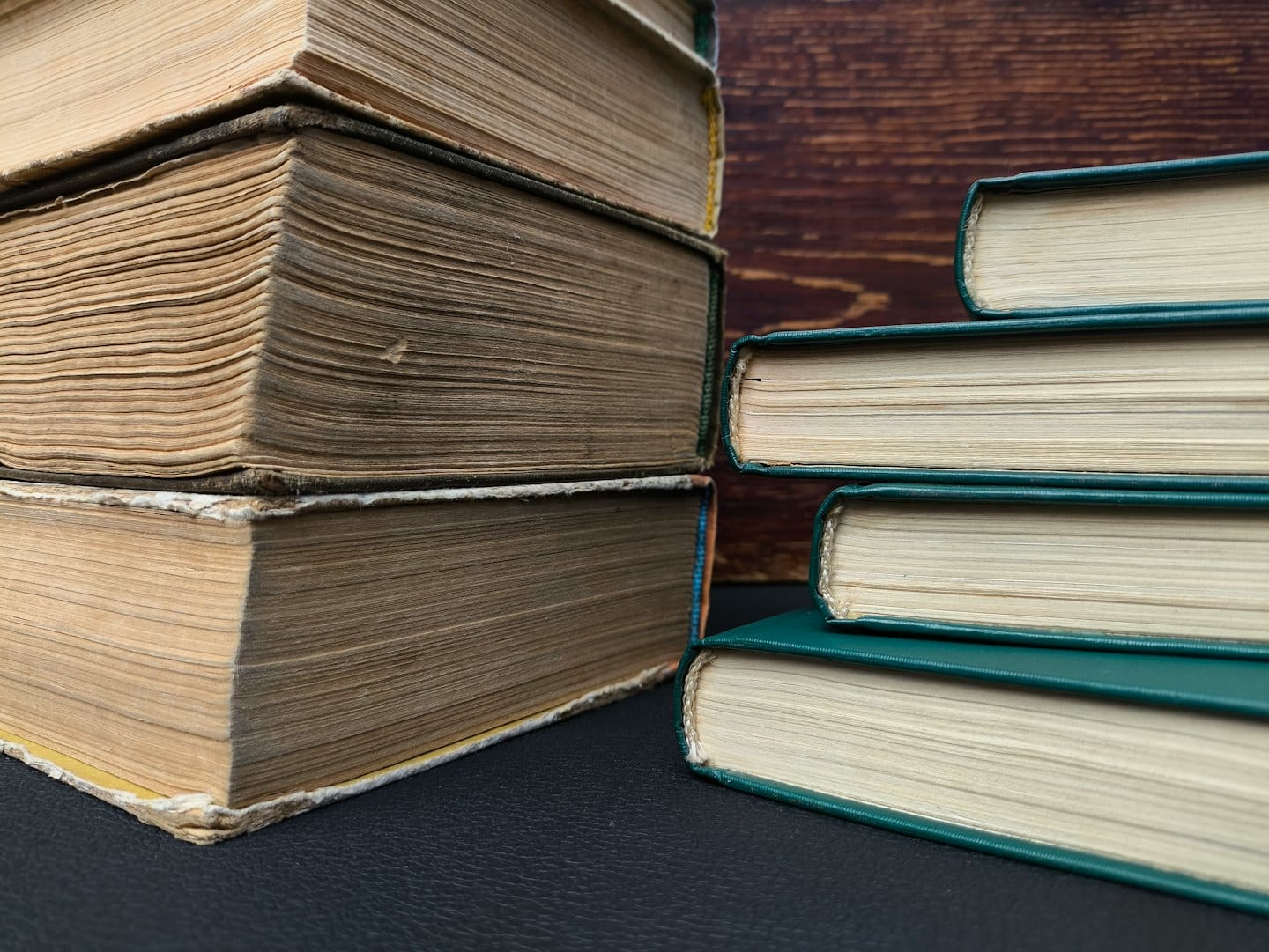 Due pile di libri antichi appoggiate su una superficie ruvida.