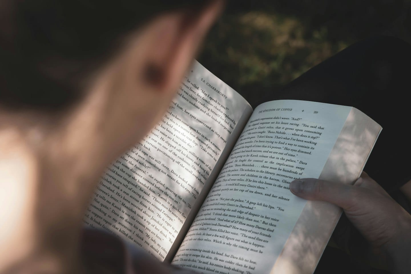 Mani che tengono aperto un libro con testo visibile.