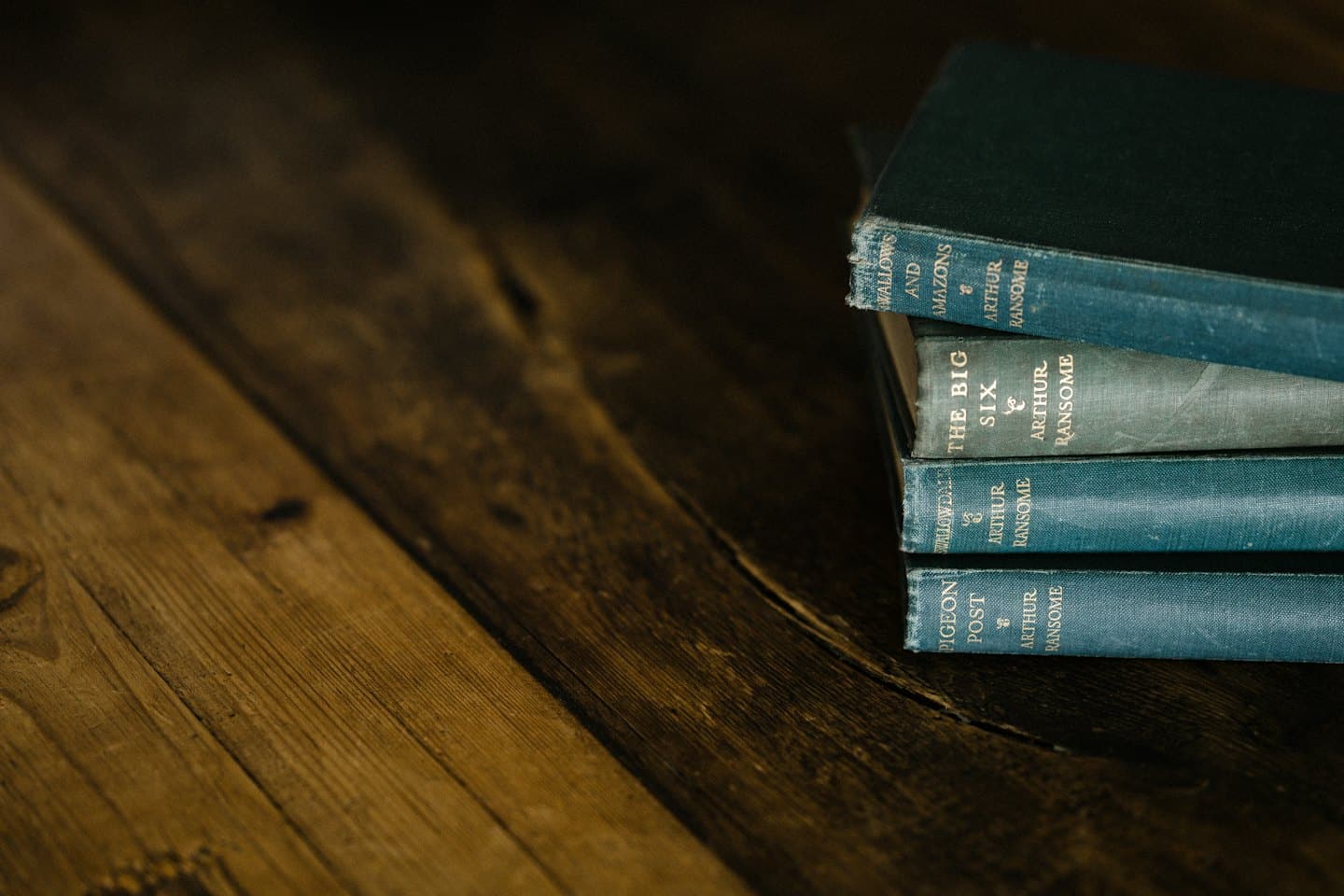 Quattro vecchi libri consumati impilati su un tavolo di legno rustico.