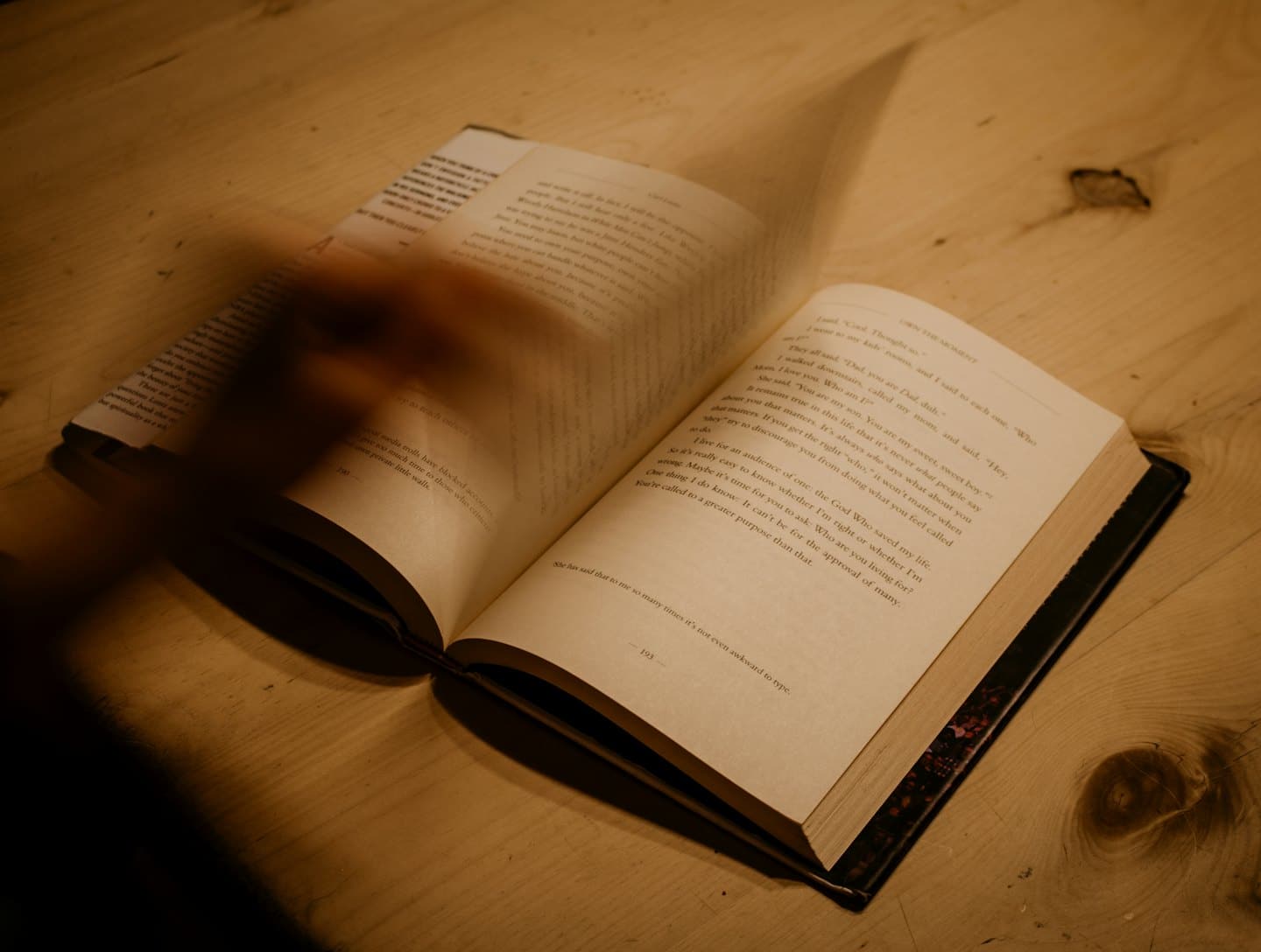 Una mano sfoglia le pagine di un libro rilegato aperto.